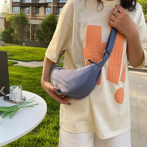 Minimalist blue nylon crescent shoulder bag shown in an outdoor lifestyle setting