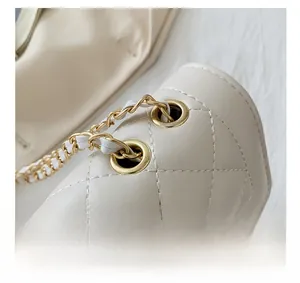 Close-up of golden metal eyelets and quilted faux leather chain strap on the beige bag