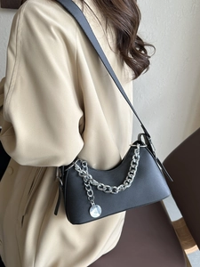 Minimalist black crescent shoulder bag with bold silver chain and matte leather texture