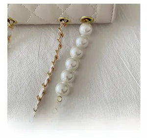 Detail of quilted leather bag with pearl chain strap and elegant metallic hardware
