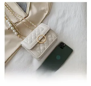 Detail view of small quilted crossbody bag showing actual size compared to a smartphone