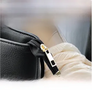 Detail shot of light gold metal zipper on black lychee grain leather tote bag
