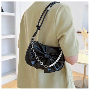 Detalle de bolso bajo el brazo negro con lazo 3D y cadena de perlas con flores