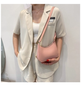 Close-up of a pink leather crescent underarm bag worn by a model on white background