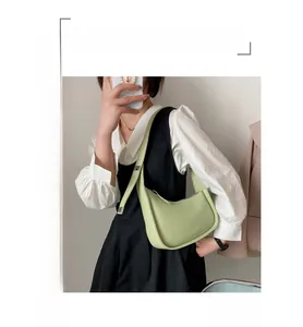 Adjustable silver buckle and strap detail on a minimalist light green crescent bag