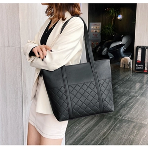 Detail of black tote bag featuring quilted diamond pattern and textured faux leather finish
