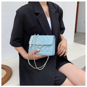 Close-up of light blue quilted crossbody bag with pearl chain and metal ring buckle