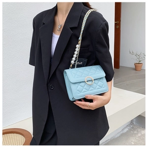 Close-up of light blue quilted crossbody bag with pearl chain and golden ring buckle