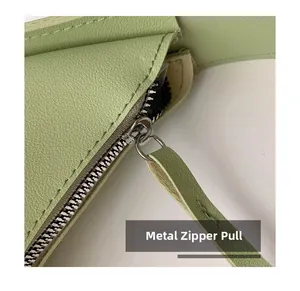 Detailed close-up of hardware zipper and lychee grain leather on light green bag