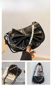 Detail der schwarzen Achseltasche mit großer Schleife und Perlenmetallkette