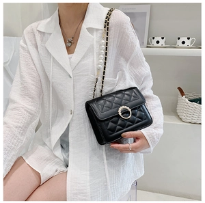 Detail of black quilted crossbody bag with pearl buckle and elegant pearl chain strap