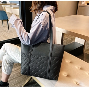 Detail of black leather tote bag with diamond quilted pattern shown on shoulder