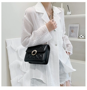 Close-up of black quilted crossbody bag with pearl buckle and metal chain strap