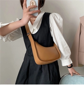 Brown leather crescent shoulder bag styled with adjustable strap on a model