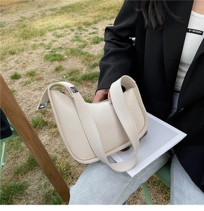 Detail of beige crescent shoulder bag showing fine leather texture and metal buckle