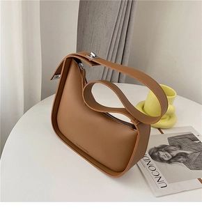 Detail of a brown semi-circle underarm bag with widened strap and silver metal buckle