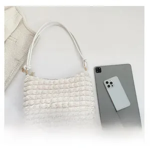 Close-up of white pleated shoulder bag with tablet and phone for size comparison