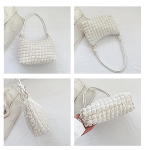 Detail of white pleated texture fabric and gold metal hardware on chic underarm bag