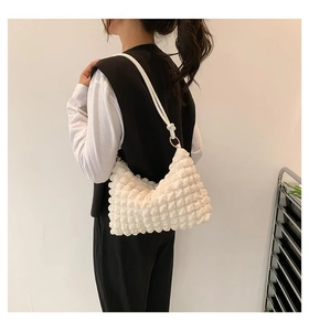 Detail of ivory pleated texture underarm bag with bubble effect and golden metal rings