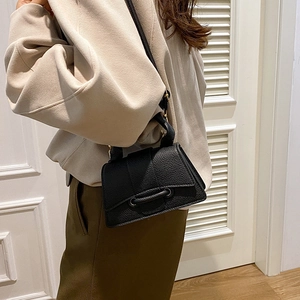 Chic black litchi texture crossbody square bag with unique buckle on a side-wearing model