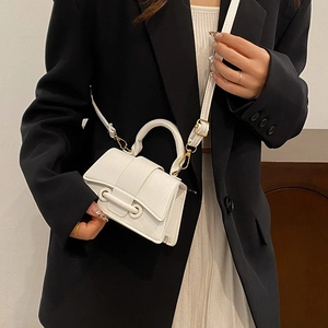 White mini crossbody bag with litchi texture shown on a model with a black blazer