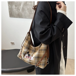 Model wearing a retro plaid tote bag with dog illustration and leather shoulder straps