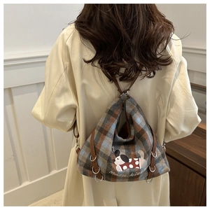 Detail of the blue and brown plaid backpack with cartoon dog print and leather straps