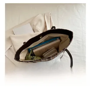 Detailansicht des geräumigen Innenraums einer grünen Karo-Tasche mit Kunstpelzbesatz