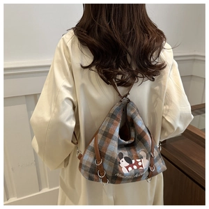 Macro detail of plaid textured backpack with cartoon dog patch and brown leather straps