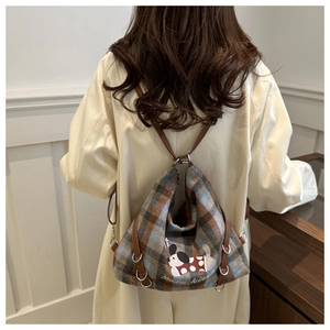 Rear view of a vintage plaid backpack featuring a cartoon dog print and metal rings
