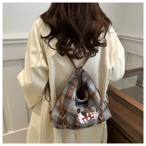 Model wearing a retro plaid backpack with a cute dog patch and brown leather straps