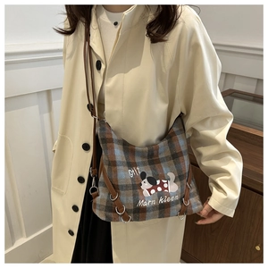 Close-up of checkered wool tote bag with cartoon dog patch and slim leather shoulder strap