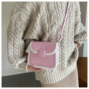 Pink faux fur trimmed crossbody bag detail on model wearing a beige knit sweater