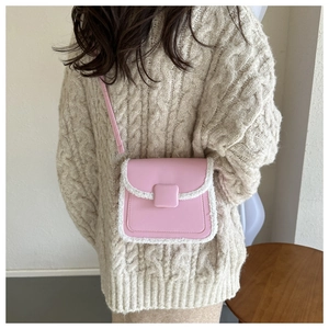 Pink crossbody square bag with white faux fur trim shown on a model's shoulder
