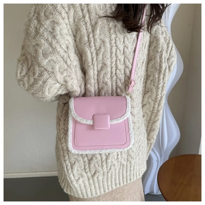 Détail du sac bandoulière rose en cuir PU avec bordure en similicuir sur pull en maille