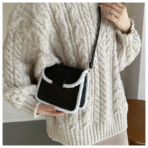 Detail of vintage crossbody bag in black leather with plush white shearling trim