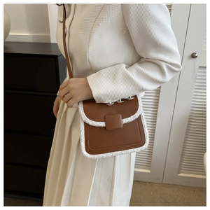 Close-up of brown leather crossbody bag with white faux fur trim on a female model