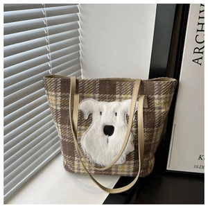 Detail der karierten Tweed-Tragetasche mit Plüsch-Hunde-Patch und Ledergriffen am Fenster