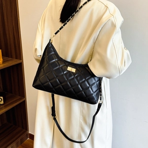 Quilted black chain shoulder bag with gold clasp shown on a model in a chic indoor setting