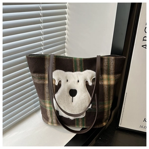 Detail der karierten Woll-Tote-Bag mit süßem Plüsch-Hund-Patch und dunkelbraunen Trägern