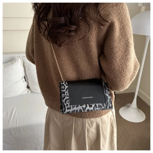 Detail of leopard print flap shoulder bag with gold chain strap on a brown sweater