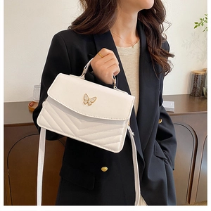 Detailed view of the white vintage shoulder bag with a gold butterfly clasp and V-quilting