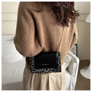 Detail of leopard print patchwork shoulder bag with gold chain strap on model