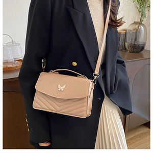 Detail of light beige crossbody bag with butterfly clasp and V-quilted faux leather
