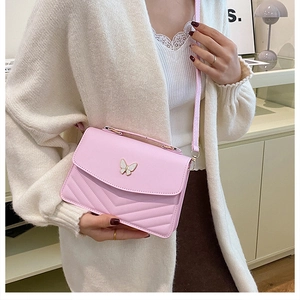 Detailed close-up of a pink crossbody bag with V-quilted texture and butterfly buckle