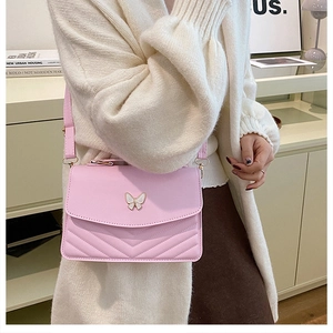Detail of a light pink crossbody bag with a white butterfly clasp and V-shape quilting