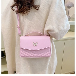 Pink quilted crossbody bag with white butterfly detail and single handle on model