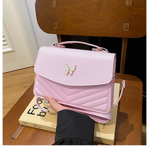 Close-up of pink crossbody bag featuring V-shaped quilting and a white butterfly ornament