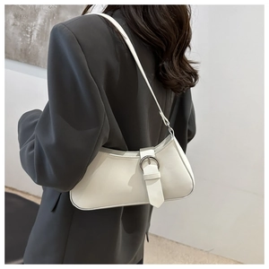 Minimalist white leather crescent shoulder bag with metallic buckle worn by a model