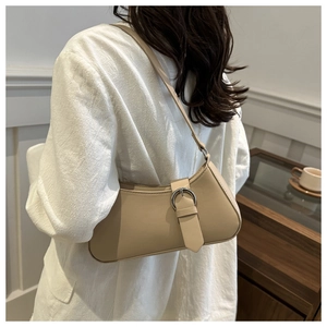 Detail of beige leather baguette bag featuring a large silver metal buckle on white shirt